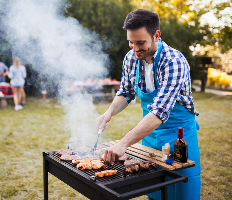 Man grilling in his backyard, using Gourmet Sun Dried Plum BBQ Sauce to create a flavorful, gourmet experience at home.