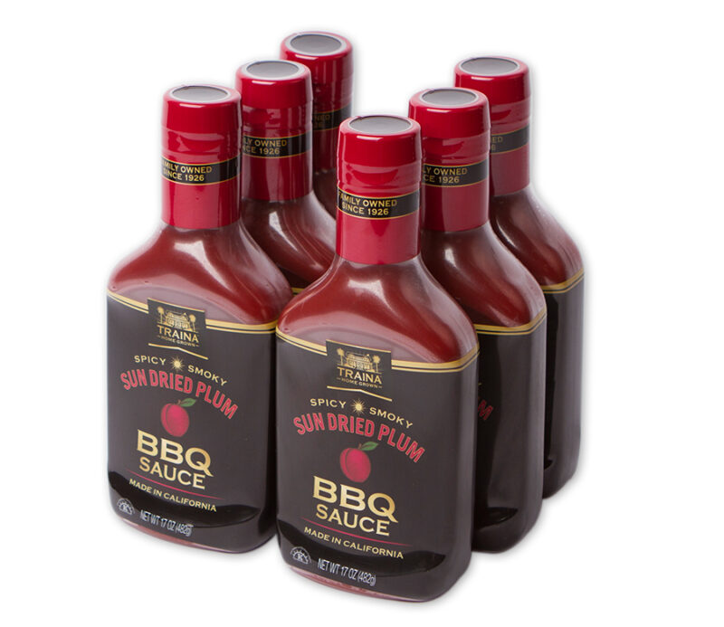 Case of six 17 oz bottles of Sun Dried Plum BBQ Sauce with black labels, made with sun dried plums, herbs, and spices. Ideal for basting or dipping, with a thick, tangy-savory flavor and dark reddish color.