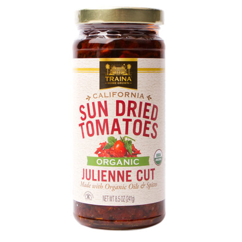 Close-up of Traina® Home Grown Organic California Sun Dried Tomatoes, Julienne Cut, in a glass jar with twist cap. Our organic tomatoes offer a savory tangy flavor. A healthy and convenient option for adding depth to various dishes.